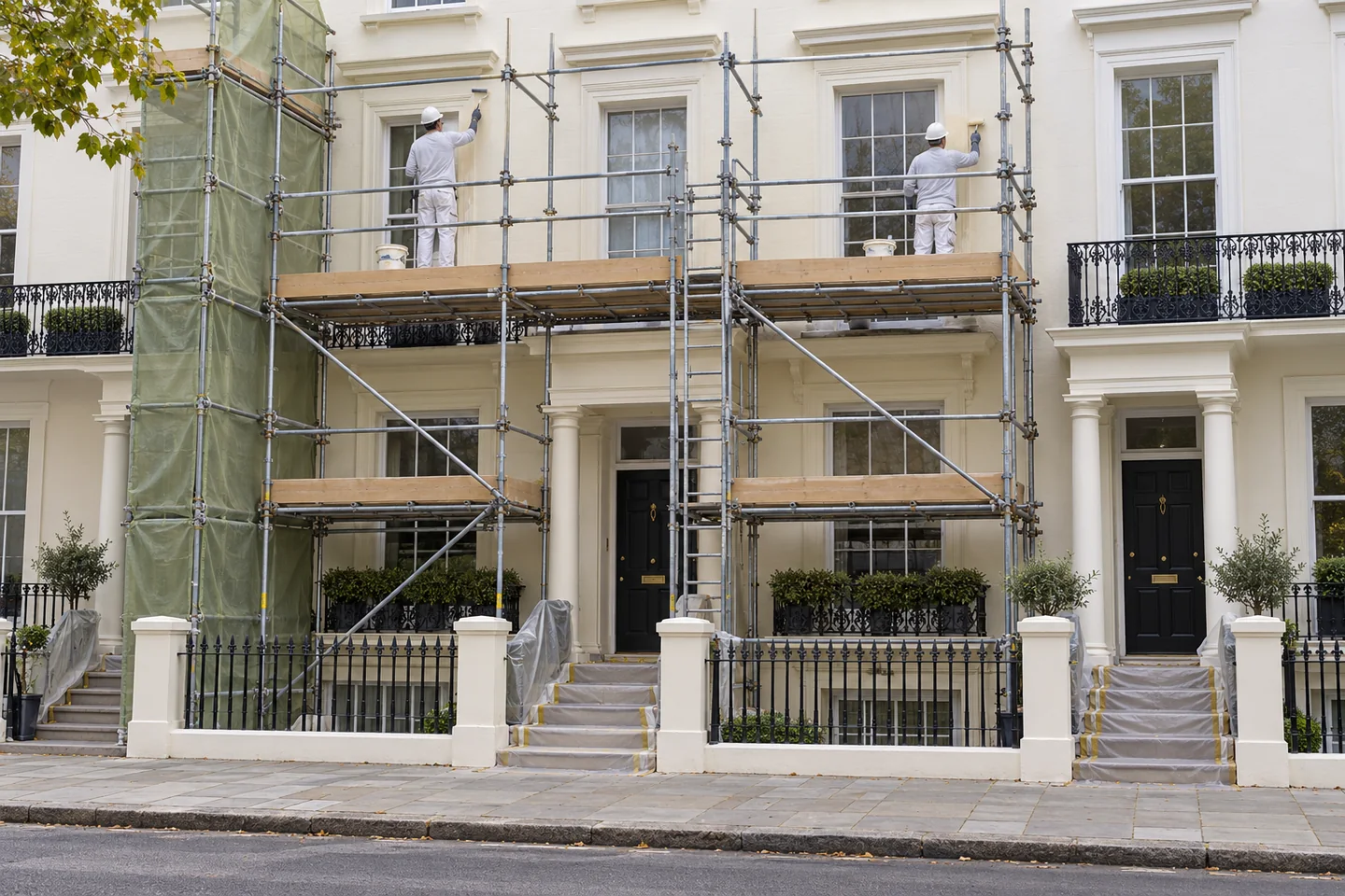 Decorators working behind scaffolding during the repainting of a stucco terrace front
